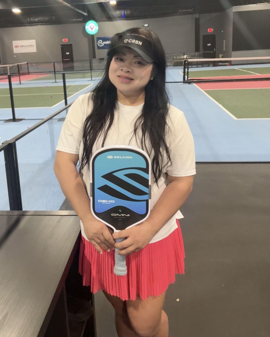 Loan Nguyen, CEO and founder of Rose City Pickleball, holding a paddle on the courts